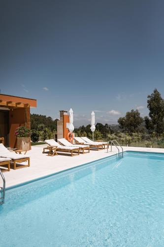 a swimming pool with chaise lounge chairs and a swimming pool at Souto Village - by RowdHouses in Maureles