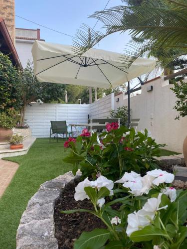 a patio with a white umbrella and some flowers at Villa Ginevra in Taranto