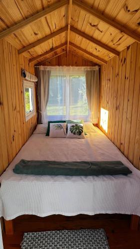 a large bed in a wooden room with a window at Recanto Roseiral - Casa Campo in Feliz
