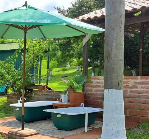 an umbrella and two bath tubs sitting under a patio at Recanto Roseiral - Casa Campo in Feliz