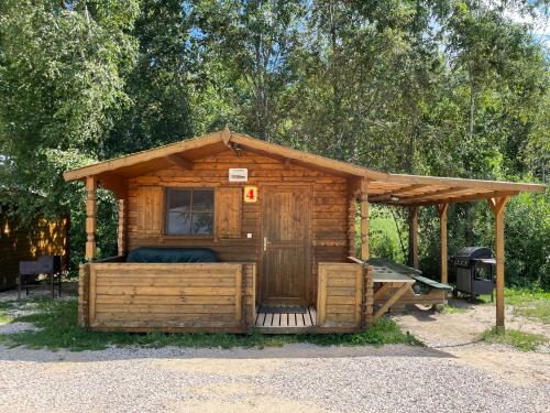 a wooden cabin with a porch and a grill at Tõhela Järve Puhkeküla in Männikuste