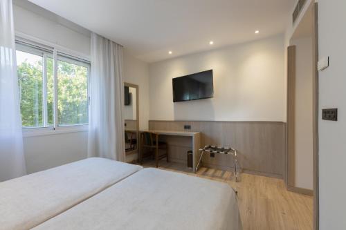 a bedroom with two beds and a desk and a television at Hotel Casanova in Fraga