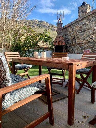 a wooden table and chairs on a patio with a fireplace at La Cata Country House in Patones