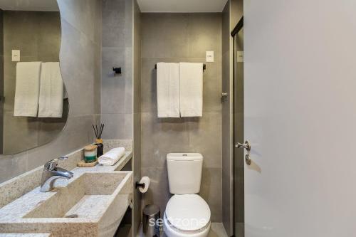 a bathroom with a toilet and a sink and a mirror at Studio de luxo e Sofisticado no Moinhos LBO203 in Auxiliadora