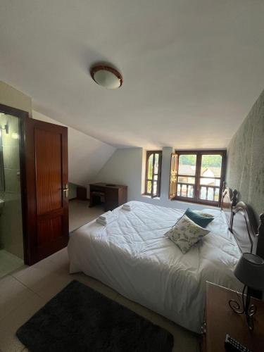 a bedroom with a large white bed and a window at El pucheru 4 Almas in Barcenaciones
