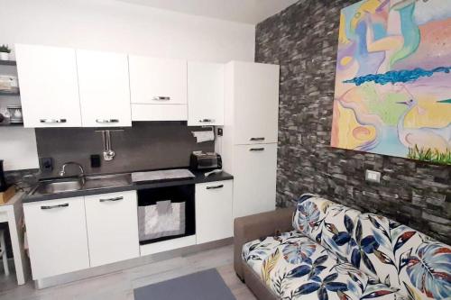a kitchen with white cabinets and a couch in a room at La Casa al mare in Santa Marinella