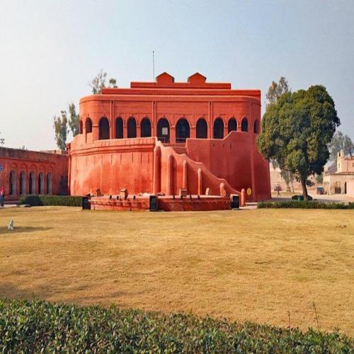a red building with a large field in front of it at HOTEL JOGI GUEST HOUSE welcome all families, friends, groups, couples, singles fully Airconditioner, attach washrooms, lift, wifi, 24 hours room service, power backup in Amritsar