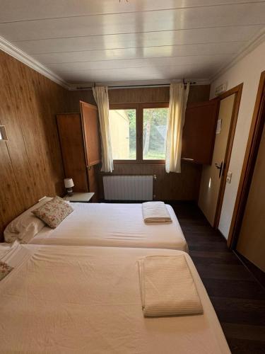 a bedroom with two beds and a window at Hostal Restaurante de Montaña Pous de la neu in Alfara de Carles