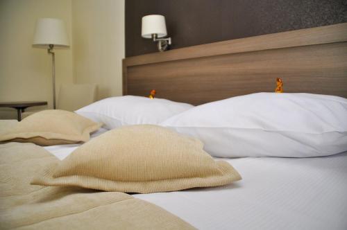 a bedroom with two beds with white pillows and a headboard at Hotel Gromada Arka Lux in Koszalin