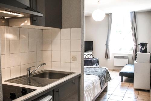 - une cuisine avec évier et un lit dans une chambre dans l'établissement LE 139 carcassonne, à Carcassonne