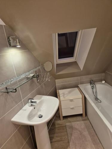 La petite salle de bains est pourvue d'un lavabo et d'une baignoire. dans l'établissement La grange fleurie, à Bolleville