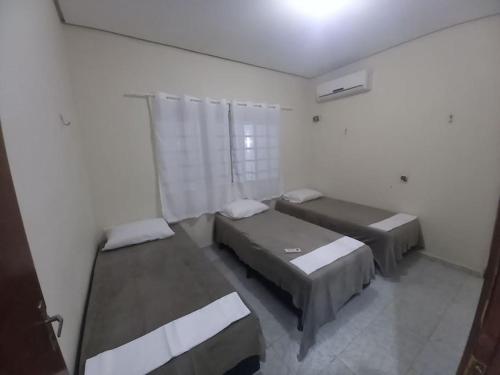 ein Schlafzimmer mit zwei Betten und einem Fenster in der Unterkunft Casa com piscina in Palmas