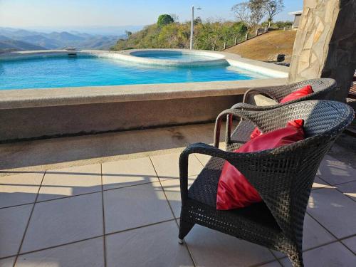 a wicker chair sitting next to a swimming pool at Casona Cocobolo el mejor lugar de Costa Rica in Guanacaste
