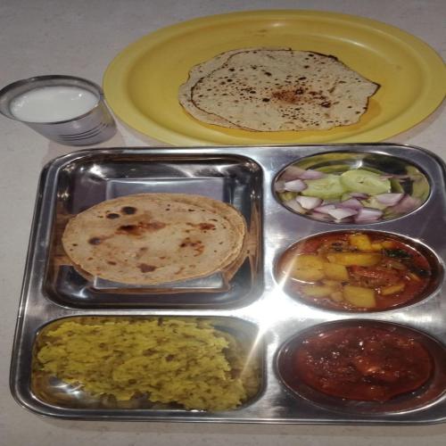 a tray filled with different types of food on a table at HOTEL JOGI GUEST HOUSE welcome all families, friends, groups, couples, singles fully Airconditioner, attach washrooms, lift, wifi, 24 hours room service, power backup in Amritsar