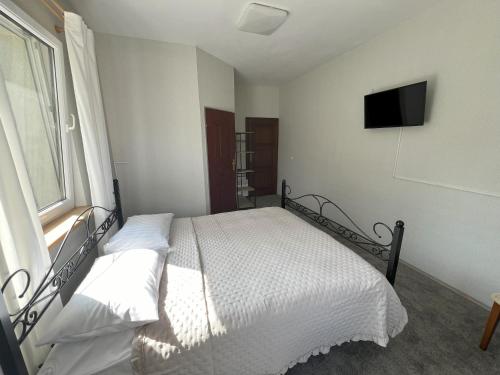 a bedroom with a bed with white sheets and a window at Jedliczanka in Jedlicze