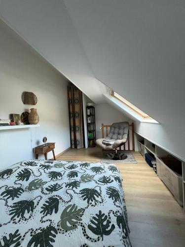 a bedroom with a bed and a chair in a attic at Gipsy Chic Duplex on the beach in Carolles