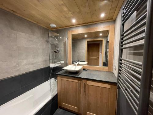 une salle de bain avec un lavabo, un miroir et une baignoire dans l'établissement Les Saisies - Appart 3P avec parking, balcon & WIFI - FR-1-293-376, à Hauteluce
