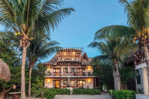 a house with palm trees in front of it at Hotel Villas Flamingos in Holbox Island