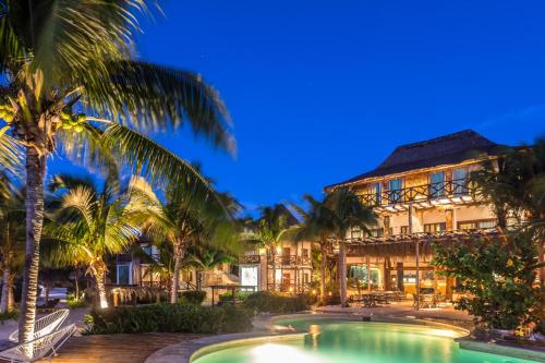 a resort with a pool and palm trees at night at Hotel Villas Flamingos in Holbox Island