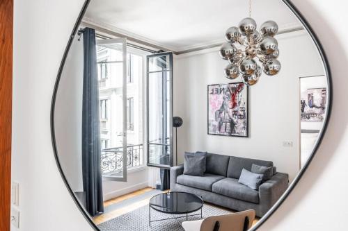 un miroir reflétant un salon avec un canapé dans l'établissement Luxury Appartement Champs Elysees, à Paris