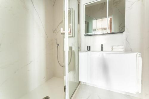 une salle de bain blanche avec un lavabo et un miroir dans l'établissement Luxury Appartement Champs Elysees, à Paris