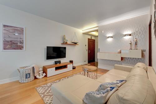a living room with a white couch and a tv at Luxury Willa Morska by Grand Apartments in Sopot