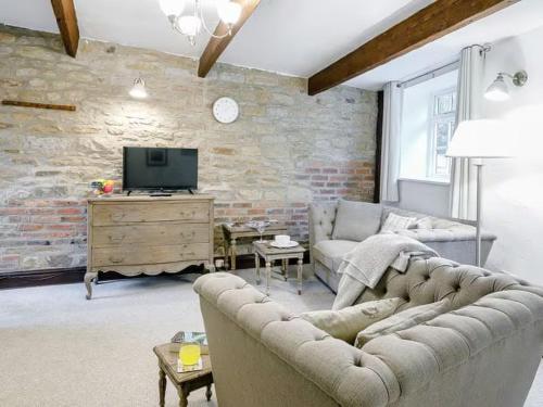 a living room with a couch and a tv at Barlow Country Club - Mill Farm Cottages in Dronfield