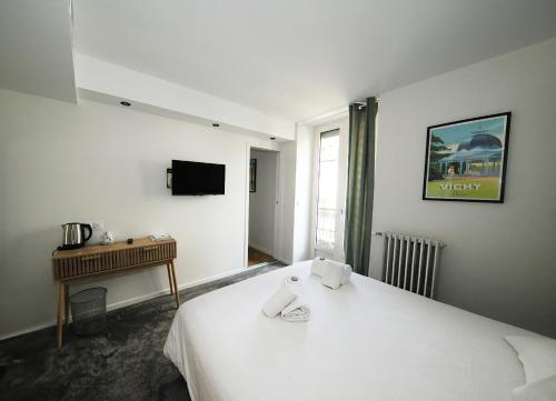 a room with a bed and a desk and a television at Hôtel & Restaurant Le Patio VICHY in Vichy