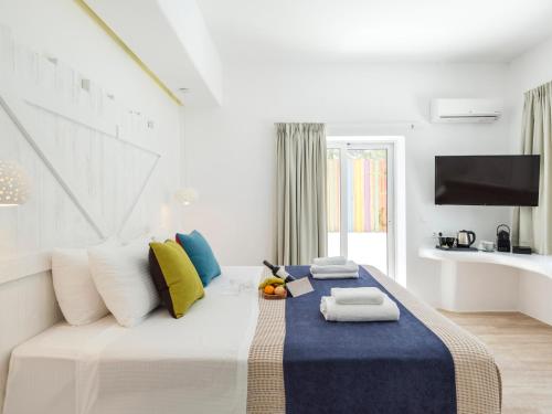 a bedroom with a large bed with pillows and a tv at Axel Beach Mykonos - Adults Only in Mýkonos City