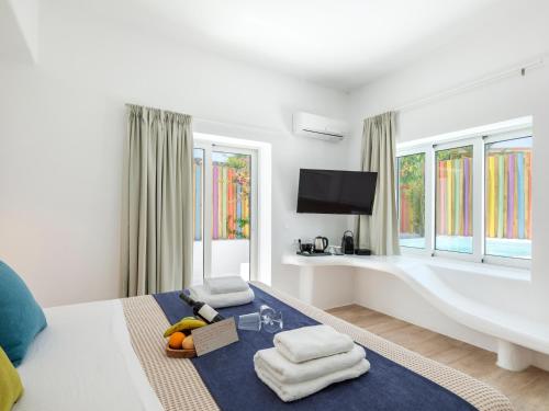 a white room with a bed with towels on it at Axel Beach Mykonos - Adults Only in Mýkonos City