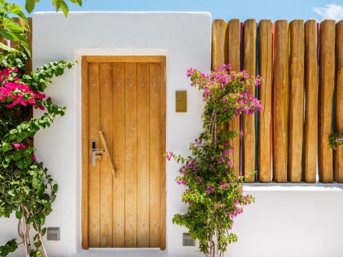 a wooden door on a white building with flowers at Axel Beach Mykonos - Adults Only in Mýkonos City