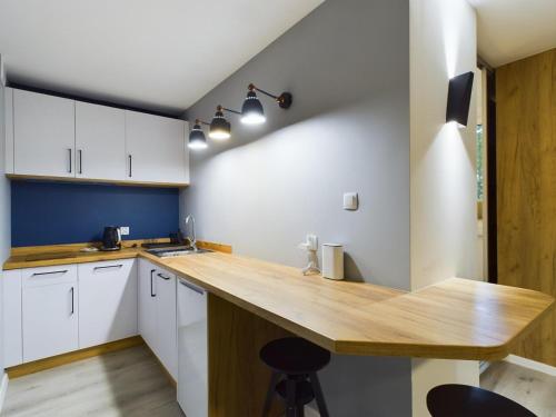 a kitchen with white cabinets and a wooden counter top at Apartamenty Familly Dąbrówka - przy parku, prywatny parking, sauna, ogód - by SpaceApart in Jelenia Góra