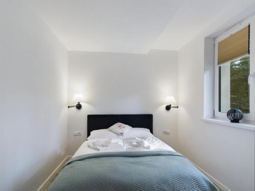a bed in a white room with a window at Apartamenty Familly Dąbrówka - przy parku, prywatny parking, sauna, ogód - by SpaceApart in Jelenia Góra