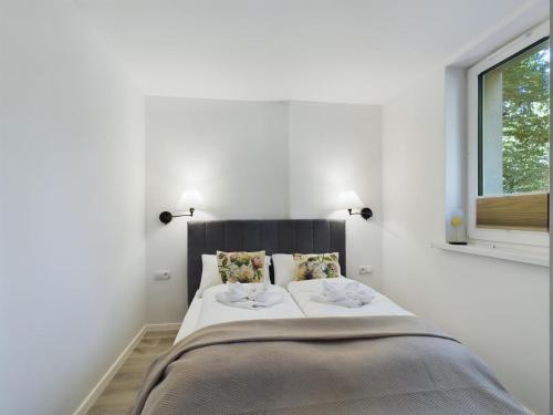 a white bedroom with a large bed with two pillows at Apartamenty Familly Dąbrówka - przy parku, prywatny parking, sauna, ogód - by SpaceApart in Jelenia Góra