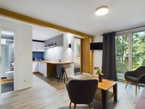 a kitchen and living room with a table and chairs at Apartamenty Familly Dąbrówka - przy parku, prywatny parking, sauna, ogód - by SpaceApart in Jelenia Góra