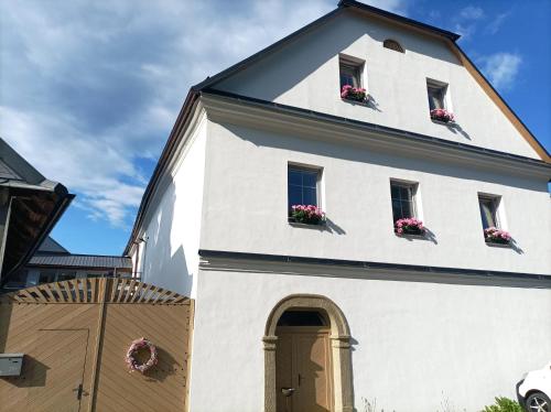 a white building with windows and flower boxes on it at Penzion na Mlýně in Hradec nad Svitavou