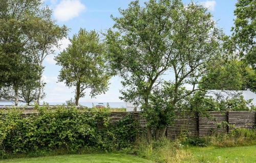 a fence with trees behind a brick wall at Holiday Home Bjørnsknudevej Juelsminde Iii in Juelsminde