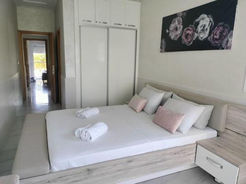 a bedroom with a large white bed with pink pillows at Appartement au bord de la mer in Saidia 