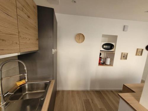 Una cocina con un fregadero y un reloj en la pared. en Logement centre le bugue, en Le Bugue