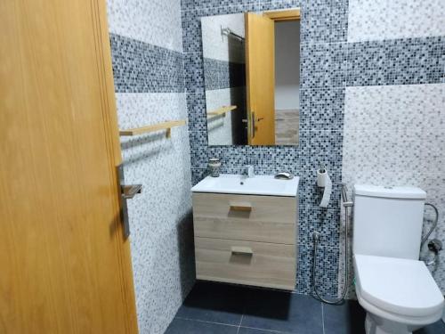 a bathroom with a toilet and a sink and a mirror at Appartement au bord de la mer in Saidia 
