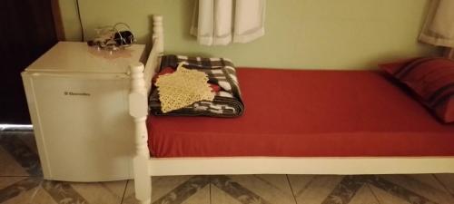 Cama pequeña en habitación con nevera en Pousada Chácara Pacheco, en Visconde De Maua