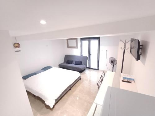 - une chambre blanche avec un lit et un canapé dans l'établissement Gîte Narbonnais 13 min des plages-Jardin-Terasse-Parking, à Narbonne