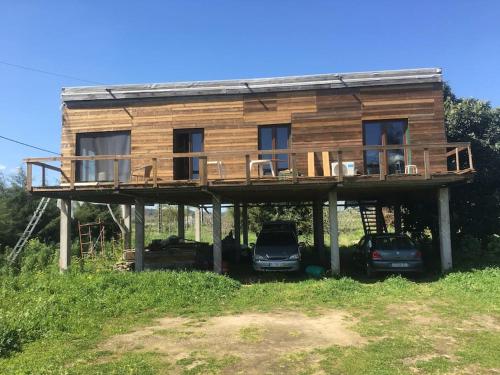 a wooden house with a deck and two cars parked at Villa Mezanine in Santarém