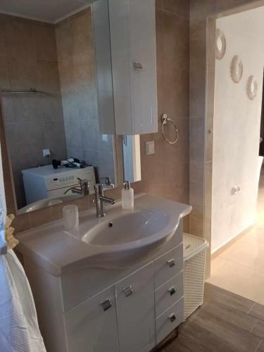 a bathroom with a white sink and a mirror at Yellow House in Eleftheroúpolis