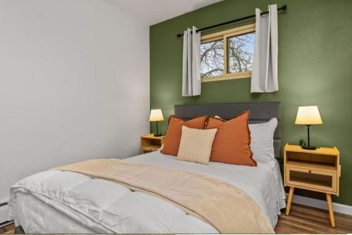 a bedroom with green walls and a bed with orange pillows at Modern Comfort Apartment in Great Falls in Great Falls