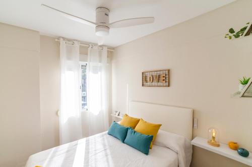 a bedroom with a bed with yellow and blue pillows at LAS VEGAS CENTRO- HOME RENt MALAGA in Torre del Mar
