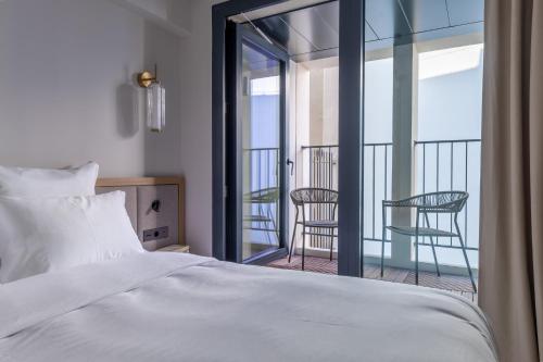 a bedroom with a bed and a balcony with chairs at Quartier Libre Opera in Paris