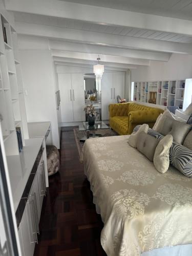a bedroom with a large bed and a yellow couch at Emerald Suite Summerstrand in Gqeberha