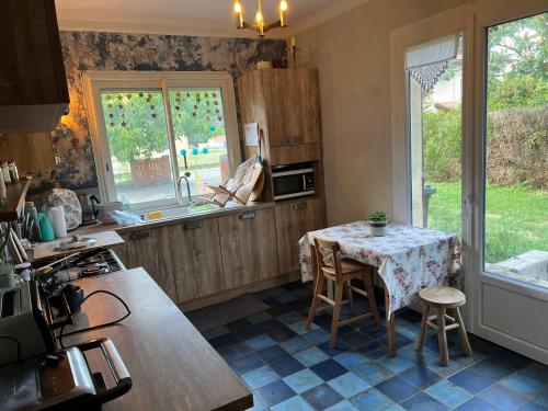 - une cuisine avec une table, une table et des chaises dans l'établissement La grande maison de la campagne, au pieds des Pyrénées Ariégeoises, à Arignac