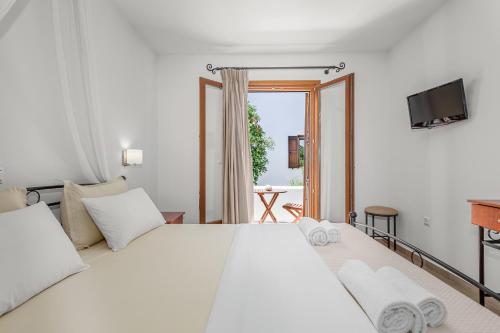 a bedroom with a large white bed and a television at Anemonisia Skyrian Living in Skiros